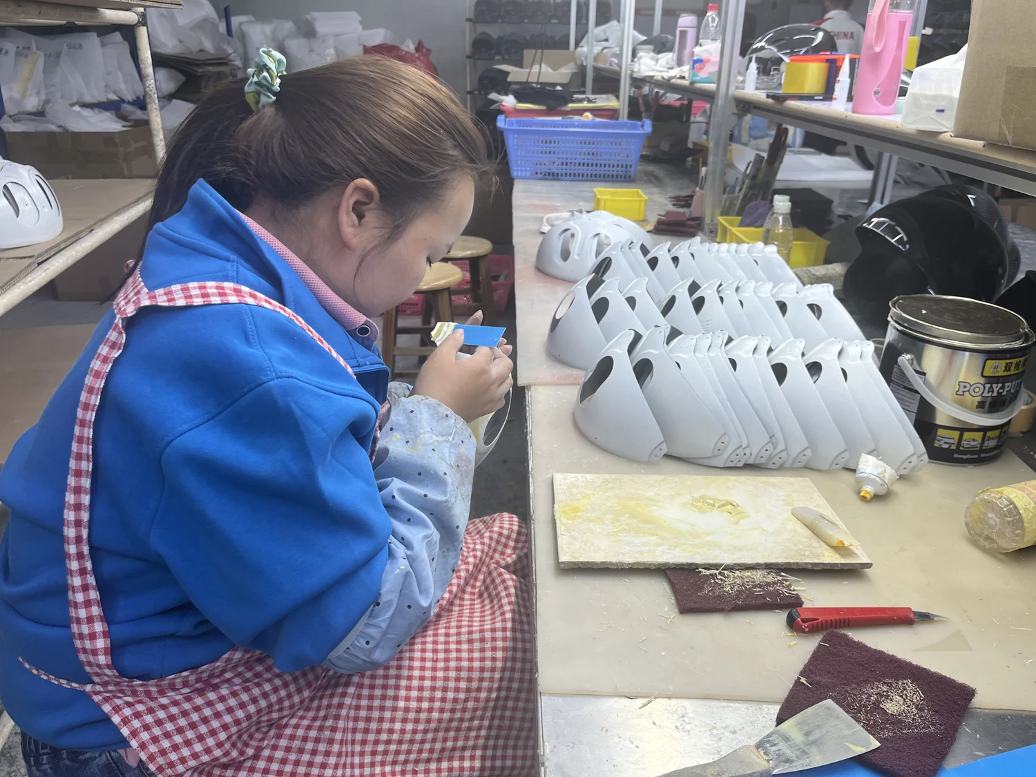 Workshop technician working on the finish of a helmet shell; this is a finishing operation, not a quality inspection